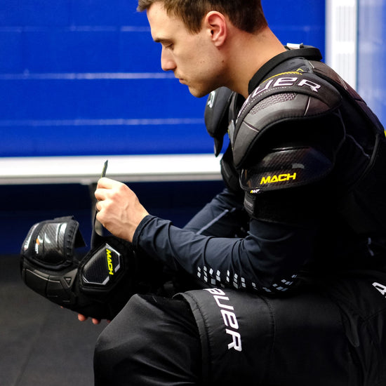 hockey player adjusting the straps on his Bauer Mach elbow pads