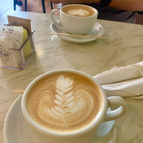 amazing and delicate latte art in 2 small white cappucino cups