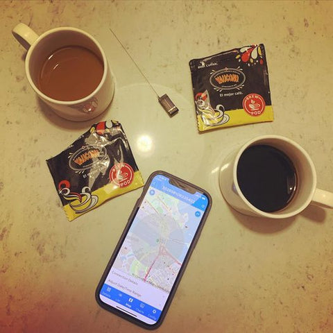 2 coffee mugs, shot from above, alongside a cell phone with map of the GPS tracking device on the screen