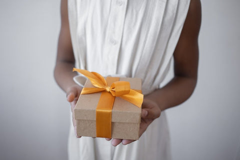 A person holding a gift with a yellow bow