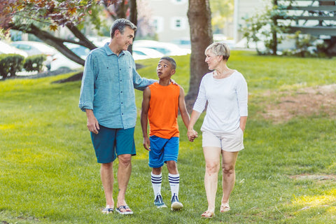 Mother, father and son walking on a grass field.