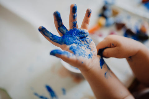 A child’s hand covered in blue paint.