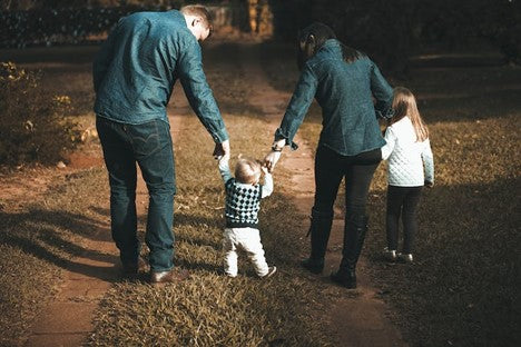 Back shot of a family of four walking and holding hands