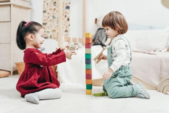 A young boy and a girl playing with wooden blocks and animal toys.