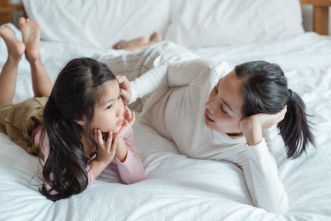 Mother and daughter lying on a bed and talking