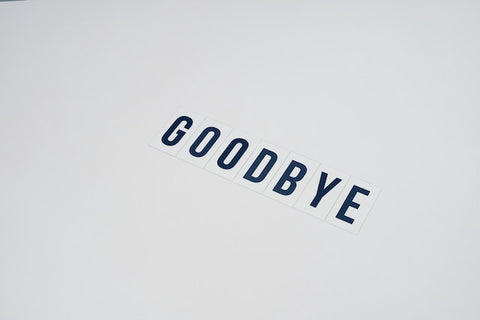 Alt text: Word GOODBYE spelled out on a white surface