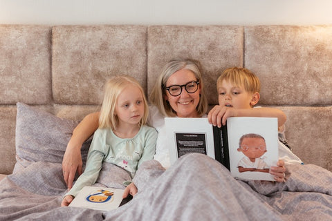 A woman with children in bed reading a book