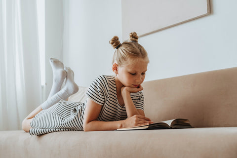 A girl reading a book on the couch