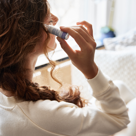 Femme qui utilise l'applicateur à bille d'huile essentielle de lavande fine sur la tempe pour relaxer