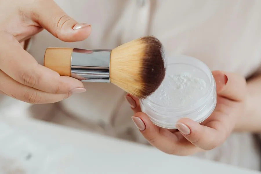 person holding a makeup brush and face powder