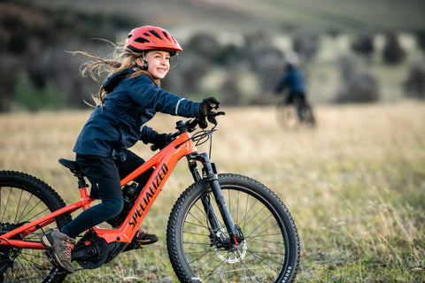 Young rider on a 24 inch kids electric mountain bike in a grassy field