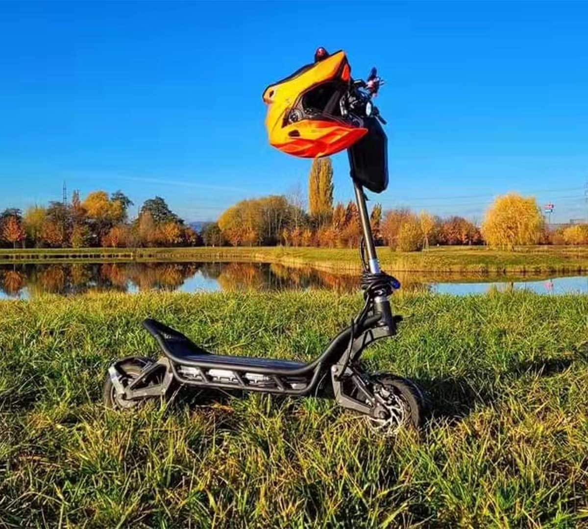 An electric scooter with a yellow helmet parked beside a lake