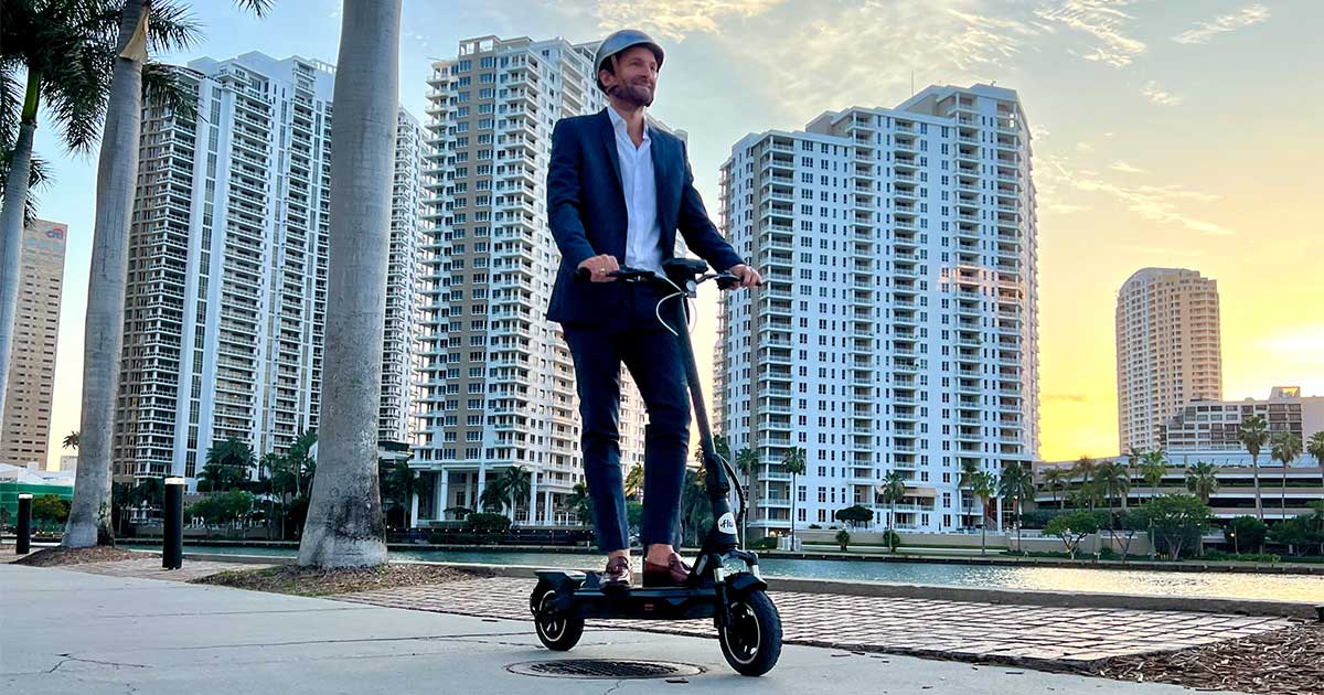 A lone rider enjoys an electric scooter ride along a waterfront at sunset, embodying the freedom and safety assured by electric scooter laws.