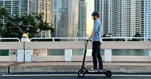 A man riding an electric scooter on the streets wearing a helmet as a safety measure