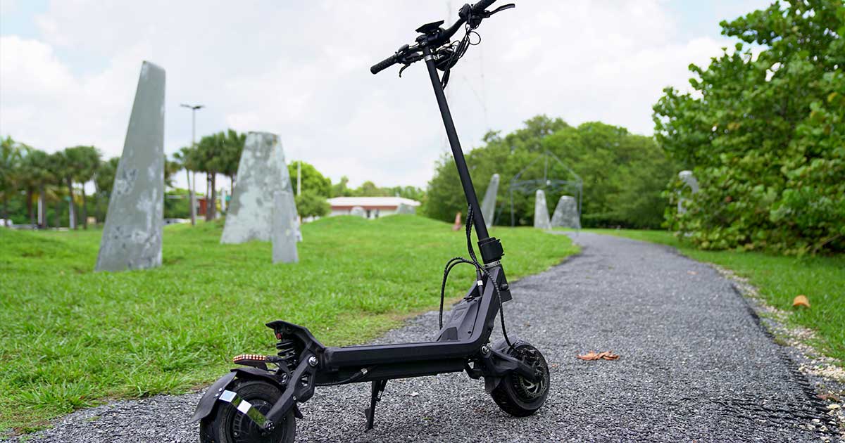 An electric scooter stands on a serene park pathway, blending sustainable transport with the tranquility of a green environment.