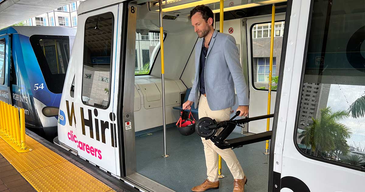 A commuter stepping off a public transit pod with an electric scooter in hand, highlighting the seamless combination of personal and public transport.