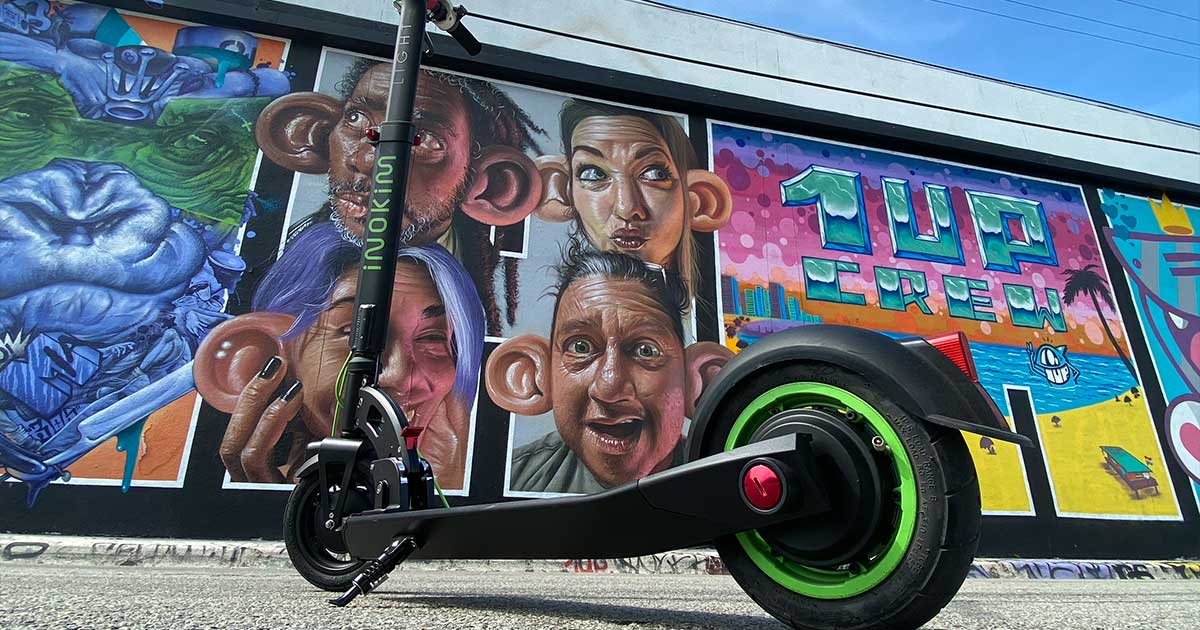 An electric scooter parked in front of a vibrant street mural, representing the cultural embrace of sustainable transport trends in city life.