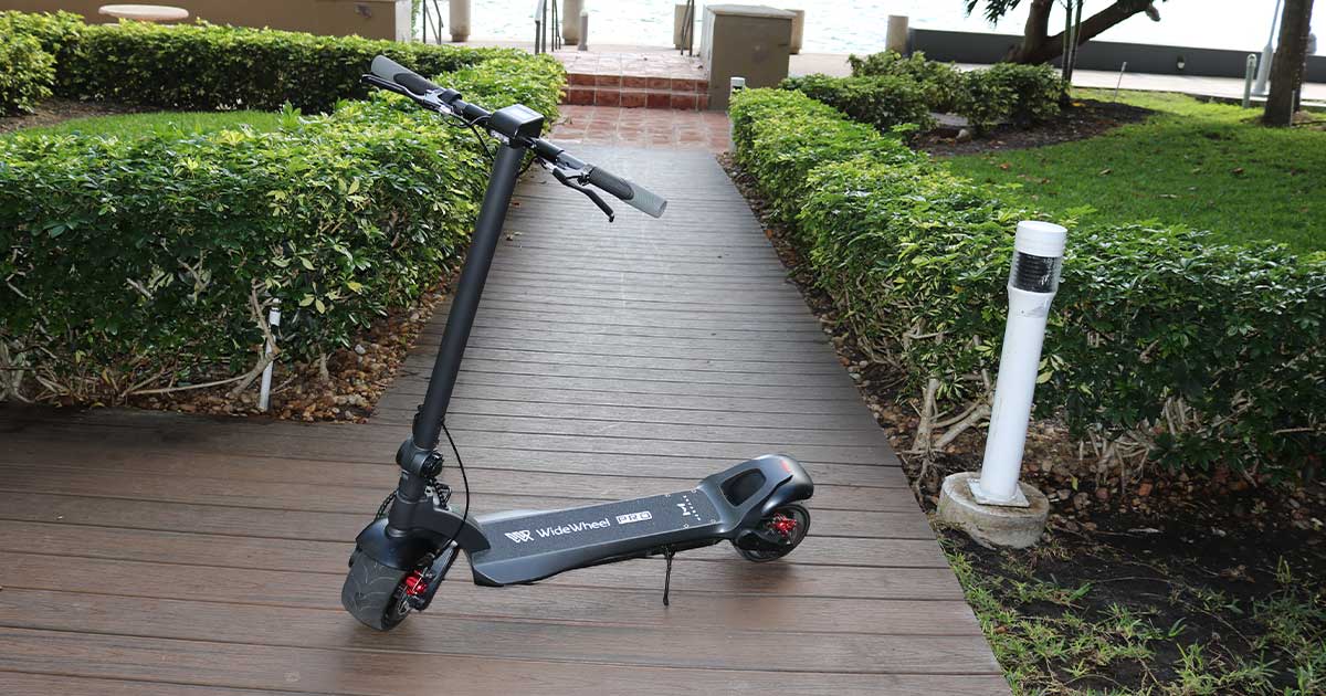 An electric scooter named 'WideWheel' parked on a wooden deck pathway, highlighting the necessity of safe parking to ensure road safety while sharing streets with electric scooters.