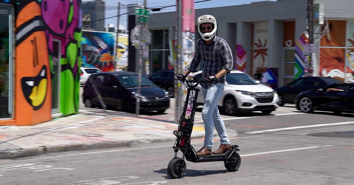 A rider on an electric scooter, wearing a helmet and navigating through city streets, exemplifies responsible road safety practices when sharing streets with electric scooters.