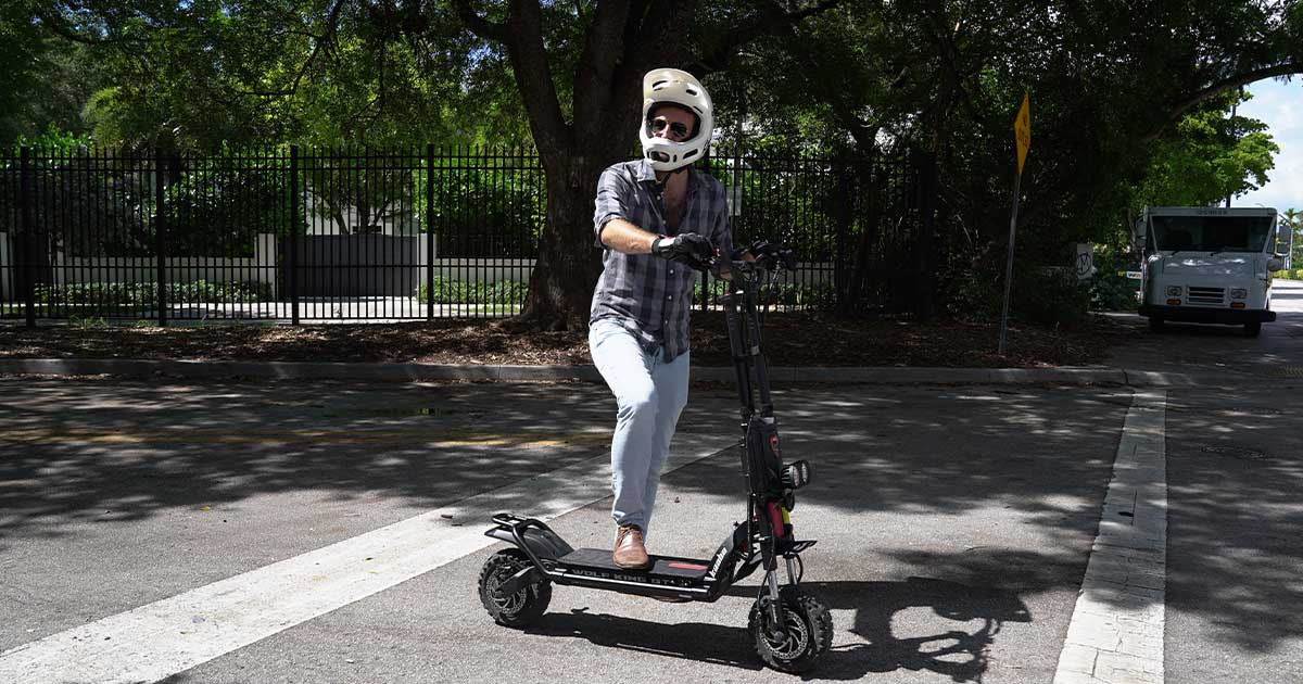 A rider wearing a white helmet maneuvers a black electric scooter across a city street, marking the intersection where cutting-edge technology meets everyday transportation needs.