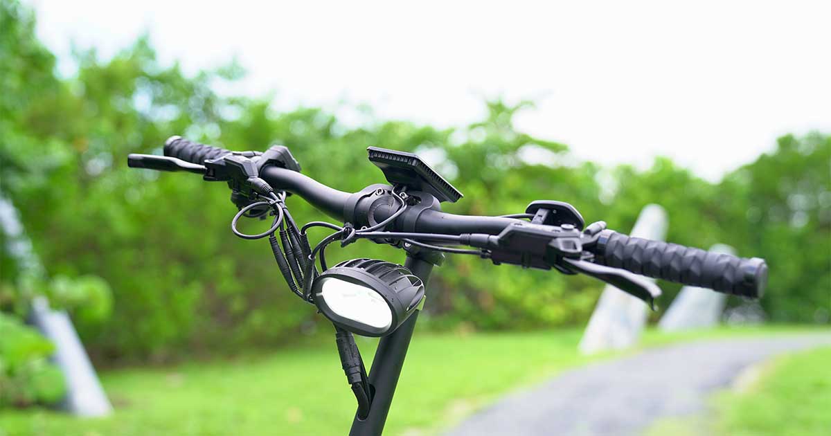 Detailed view of an electric scooter's handlebar, highlighting the safety components like brakes and lights that adhere to safety standards.