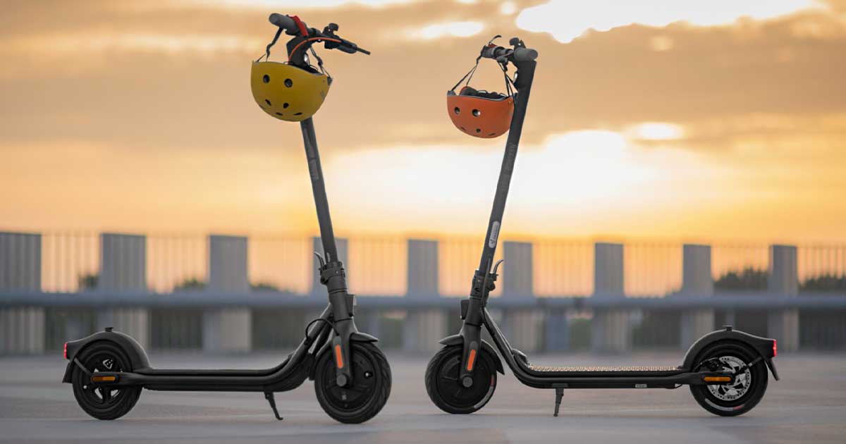 Two electric scooters standing side by side, equipped with safety helmets on their handles, representing the high safety standards maintained by top brands.