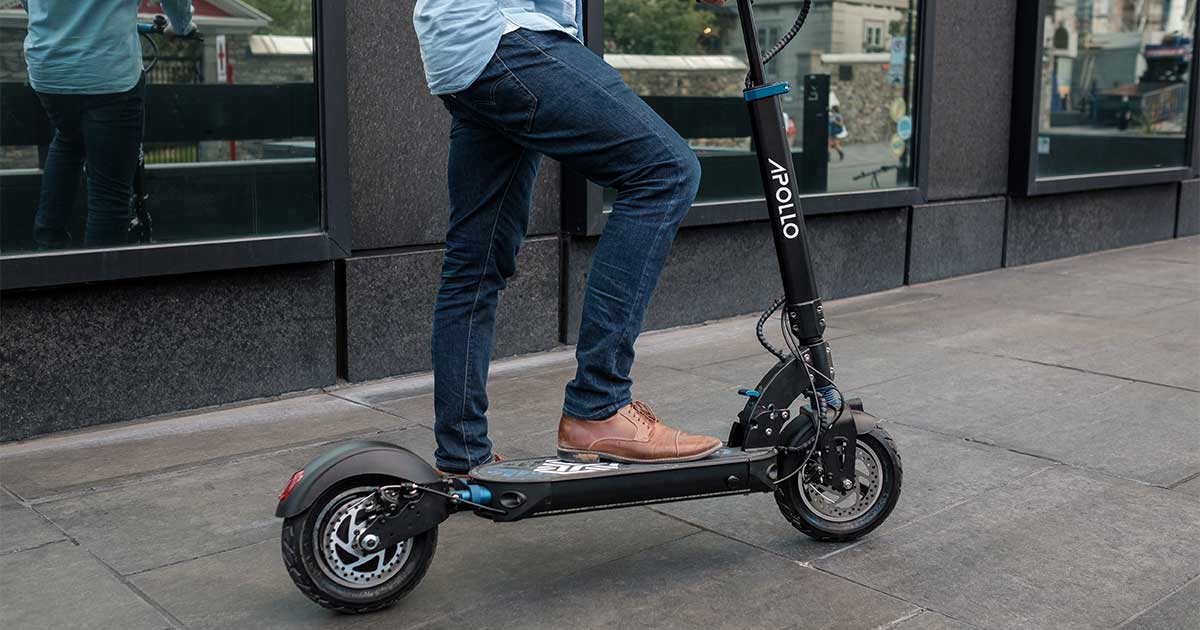 A person standing on an electric scooter with the brand name 