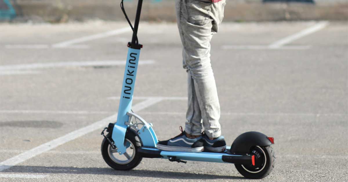 A person stands on an electric scooter in an urban setting, representing the daily use and lifespan of electric scooters in city commuting.