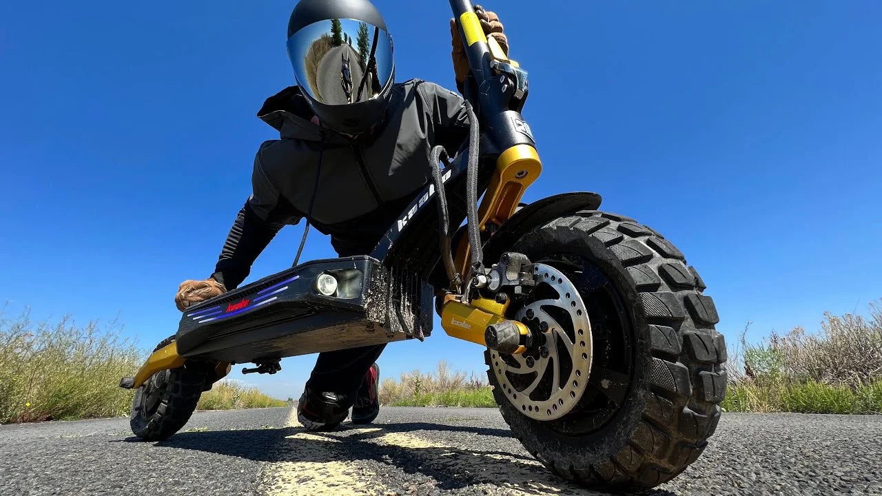 A close up image of a rider and an electric scooter with a thick ad large front wheels