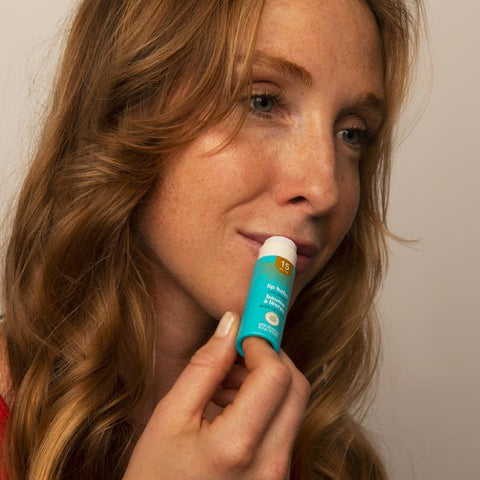 Woman applying a lip balm with SPF 15 without worrying ingredients