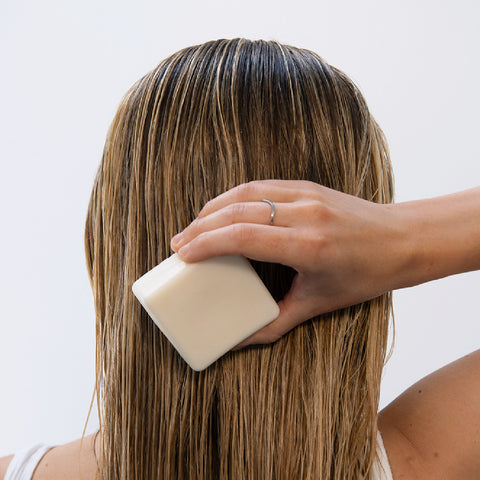 Woman using ATTITUDE's shampoo bar that doesn't contain any ingredients to avoid in a shampoo