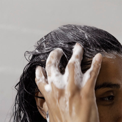 Woman washing her hair with volumizing shampoo bar ATTITUDE