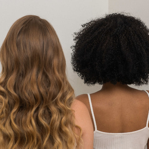 Two woman facing the opposite side with different types of curly hair