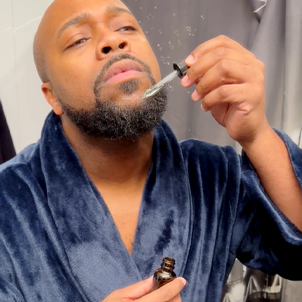 A black guy applying a beard oil
