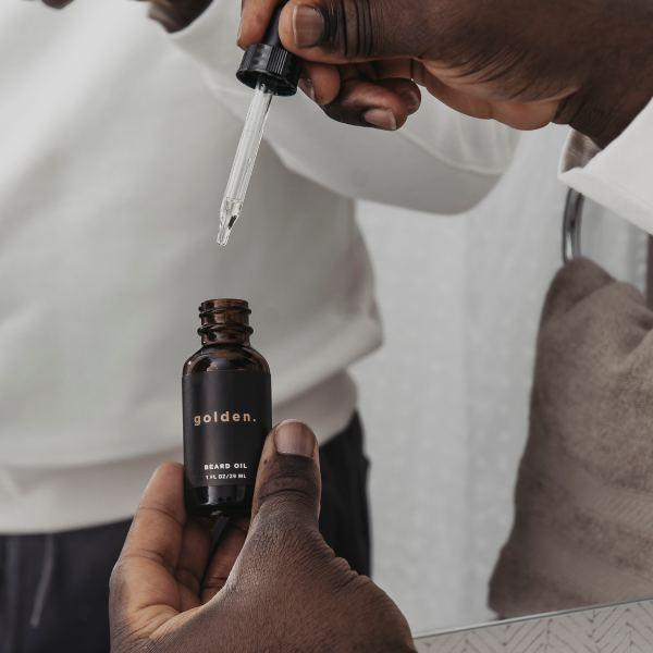 A man holding a bottle of Golden Beard Oil