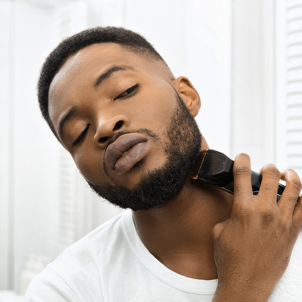 A black man trimming his beard