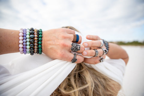 Man with hands behind his head wearing gemstone bracelets