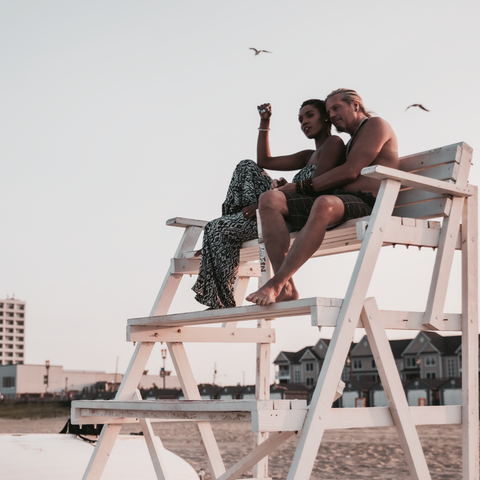 couple sitting in lifeguard chair enjoying sunset