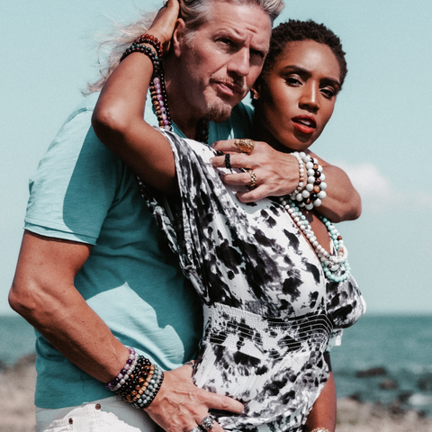 couple standing on beach rock with arms around one another