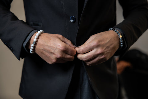 Man wearing a suit and two gemstone bracelets.