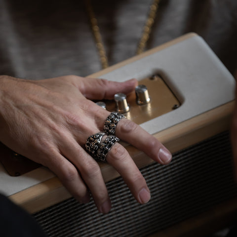 Man holding music speaker wearing men's rings.
