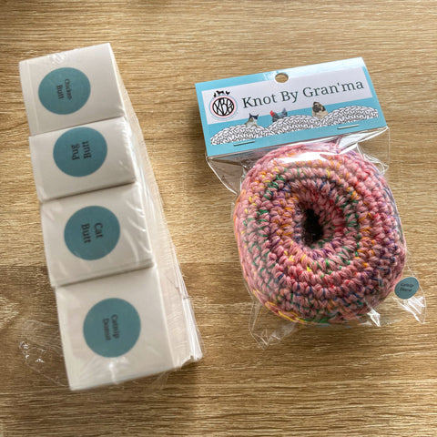 photo of a packaged crocheted pink catnip donut with KBG branding next to 4 stacks of teal circle stickers