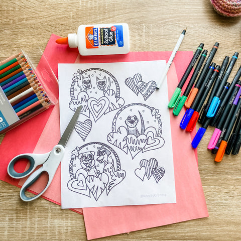 Photo of Valentine's Day coloring page on top of pink and red construction paper with scissors, Sharpy pens, colored pencils and school glue.