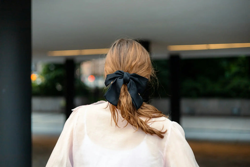 Image of a woman wearing a black scarf tied in a bow in her hair
