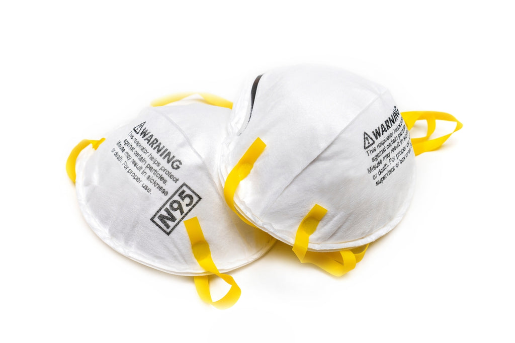 Two N95 masks with yellow adjustable straps on white background.