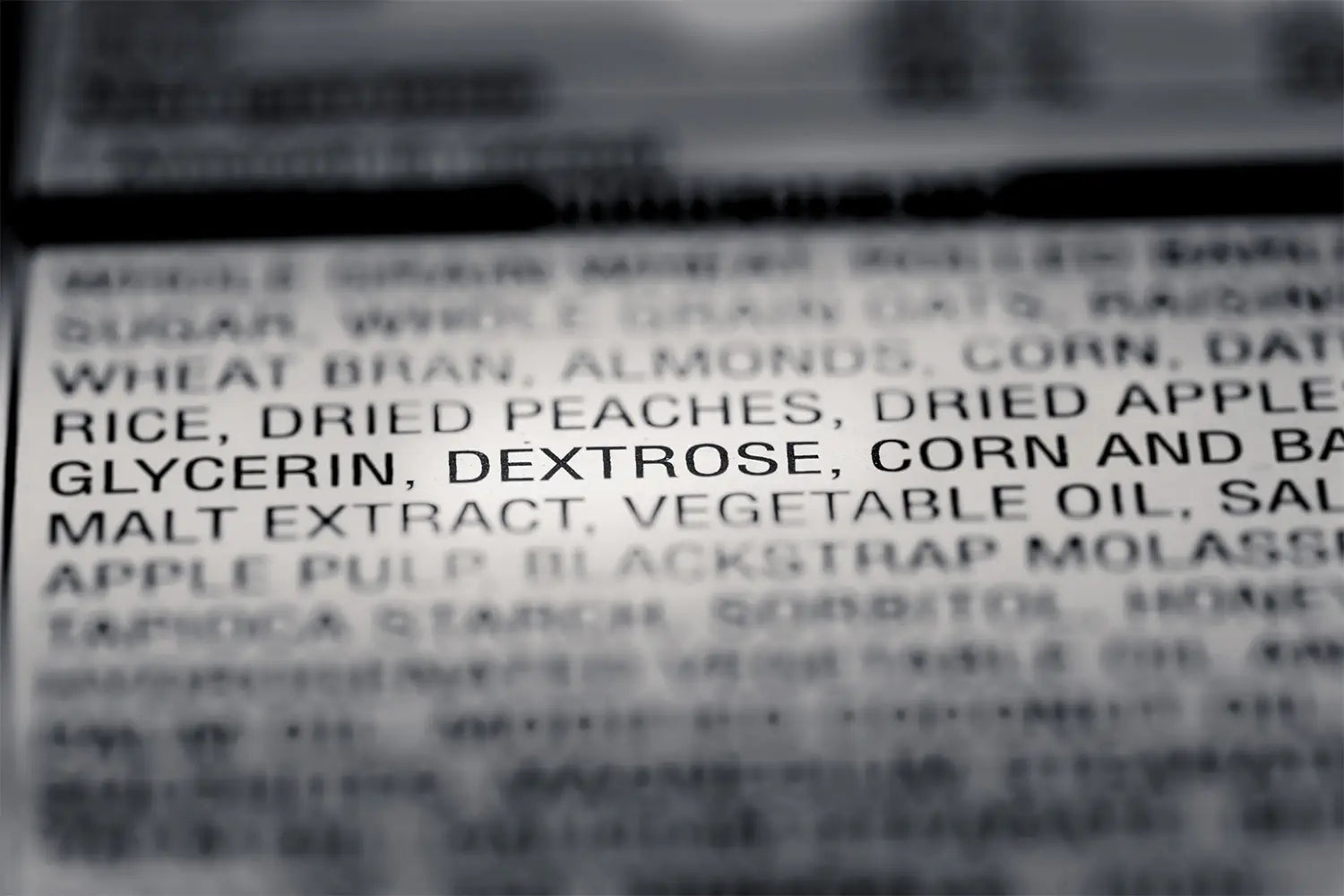 A close-up of a food ingredient list with the words "GLYCERIN, DEXTROSE, CORN AND" in sharp focus while the surrounding text is blurred.