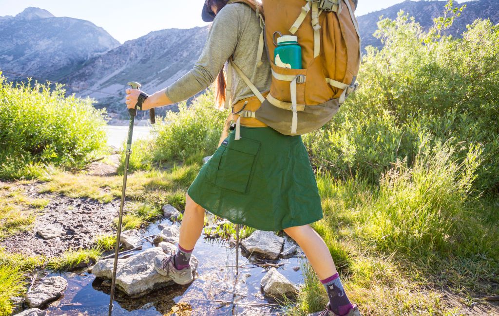 Woman wearing LightHeart Gear hiking skirt with pockets while crossing a stream in the mountains.