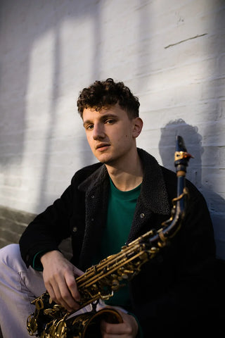 Alex Bone holding black alto saxophone