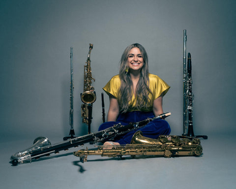 Emily Pecoraro seated with her saxophones and clarinets and flutes.