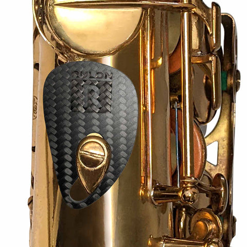 The RULON saxophone rest made of carbon fiber helps reduce thumb, hand, and wrist pain while playing the saxophone instrument.